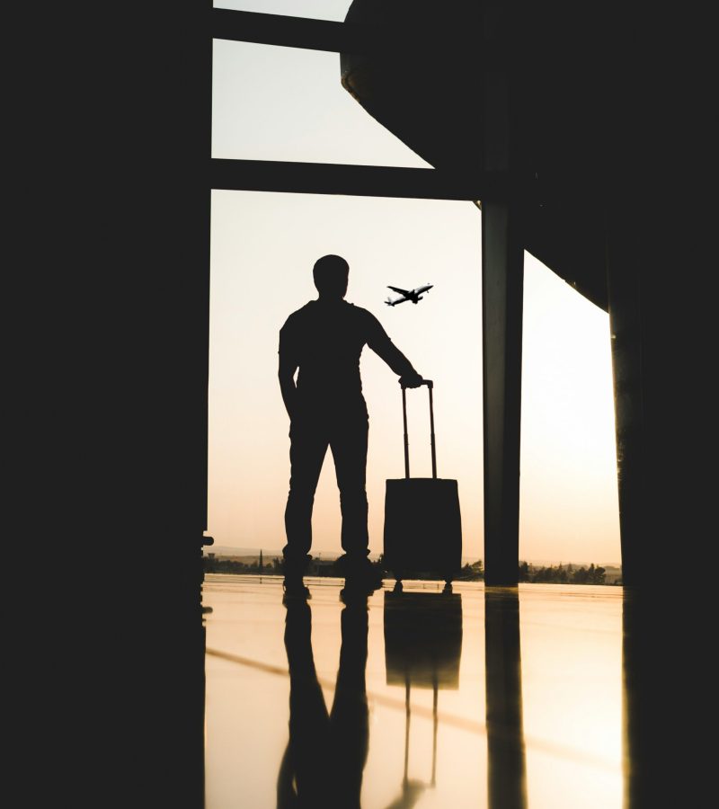A Man with a suitcase watching the sunset in a airport